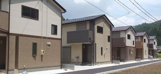 白やグレー、茶色を基調とした2階建て住宅が5棟建っている村営住宅の外観写真