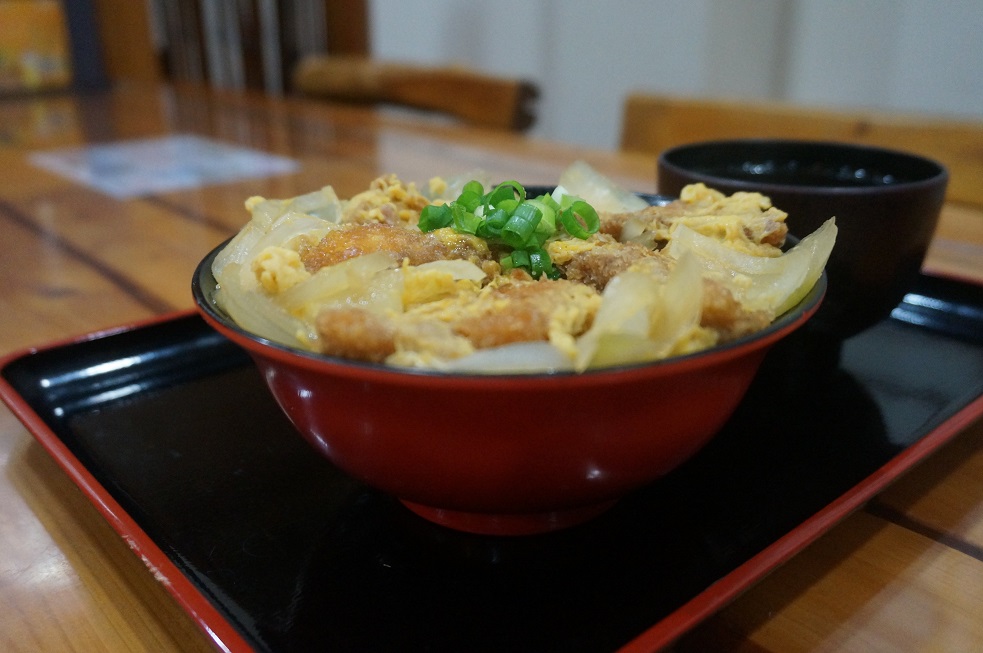 パン粉を付けて揚げたチョウザメを卵でとじ、赤褐色のお椀に盛られた「ロイヤルフィッシュかつ丼」の写真