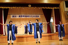 長めの紫の法被を着た演者の方がステージの上と下で両手を広げて踊っている写真