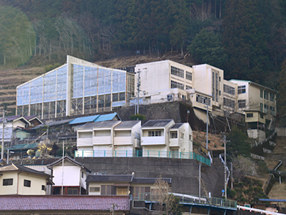 高台に建てられた白を基調とした校舎の富山小・中学校全体写真