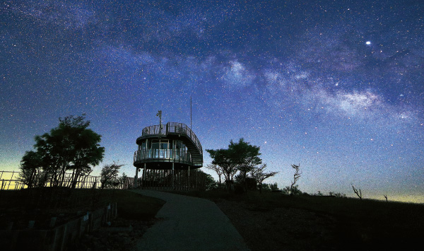 山頂に2階建ての展望台があり、太陽が沈んだ上空に沢山の星が浮かんでいる写真