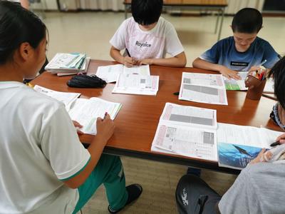 長机と椅子を向かい合わせに設置し、4人の子ども達が席に座り、一緒に勉強をしている写真