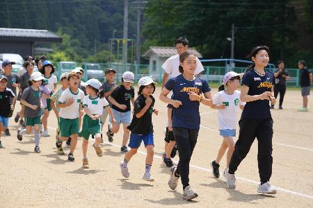 名城大学生が小学生を率いて走っている写真