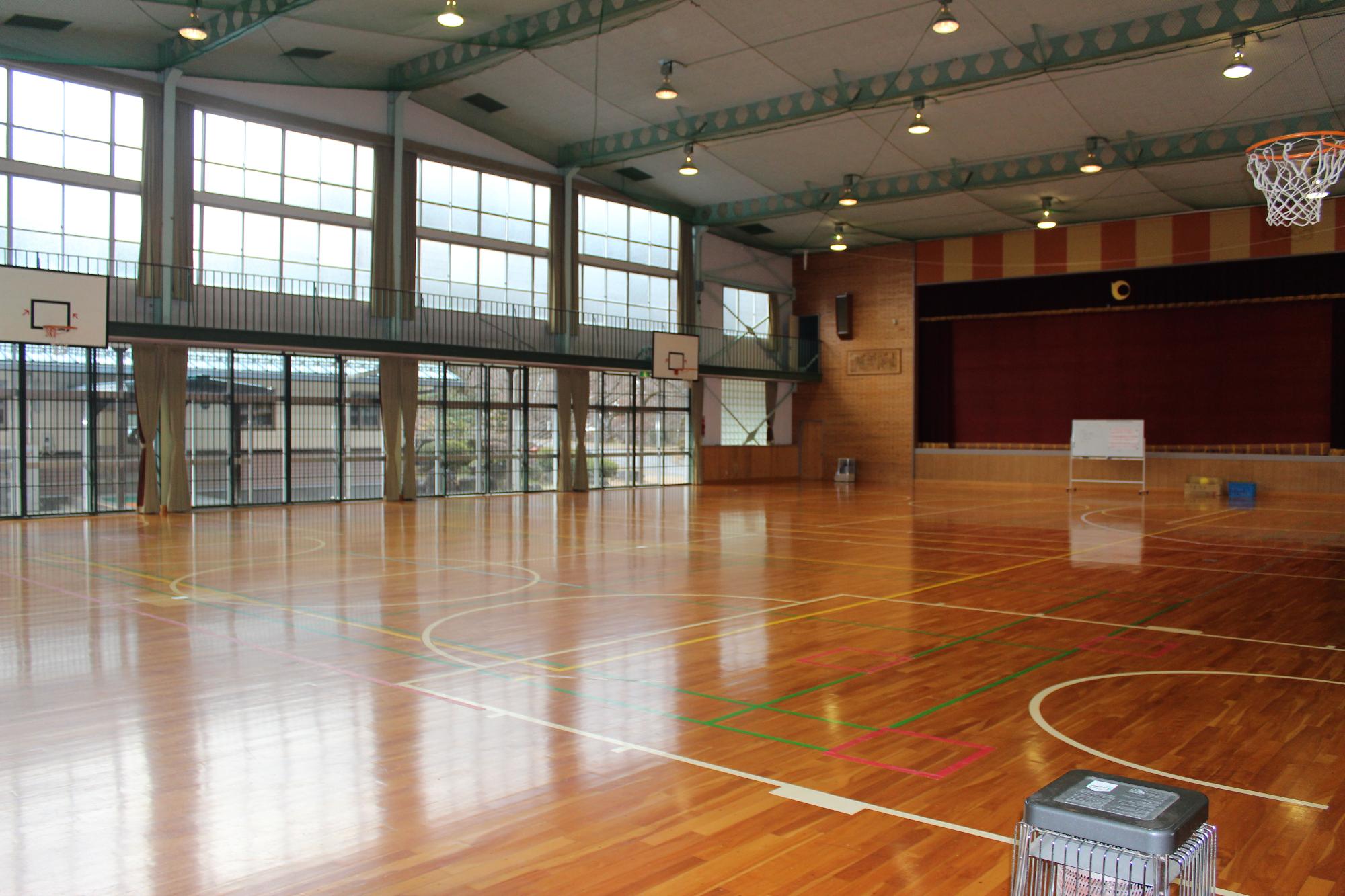 板張りの体育館。ステージの前にホワイトボードが置かれている。